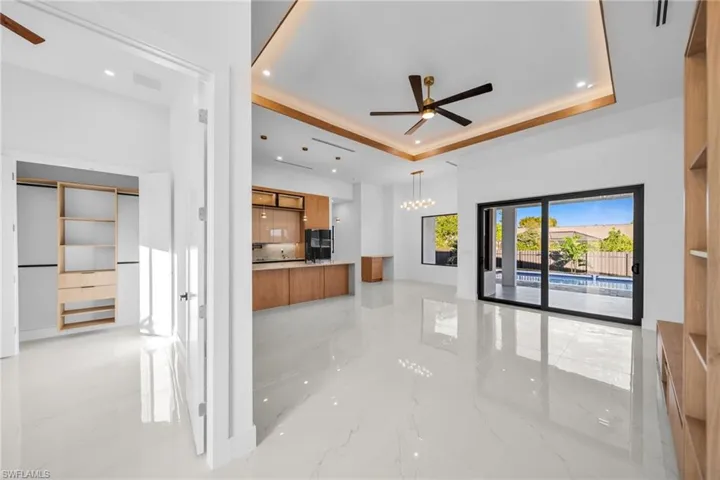 Unfurnished living room with ceiling fan, light marble finish floors, recessed lighting, a chandelier, and a raised ceiling