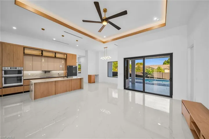 Kitchen featuring modern cabinets, light marble finish flooring, decorative backsplash, light stone countertops, and a chandelier