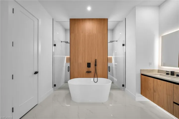 Full bathroom featuring a shower stall, a soaking tub, vanity, recessed lighting, and light marble finish flooring