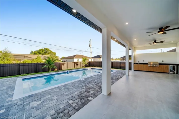 View of pool with an outdoor kitchen, a patio, a fenced backyard, and a ceiling fan