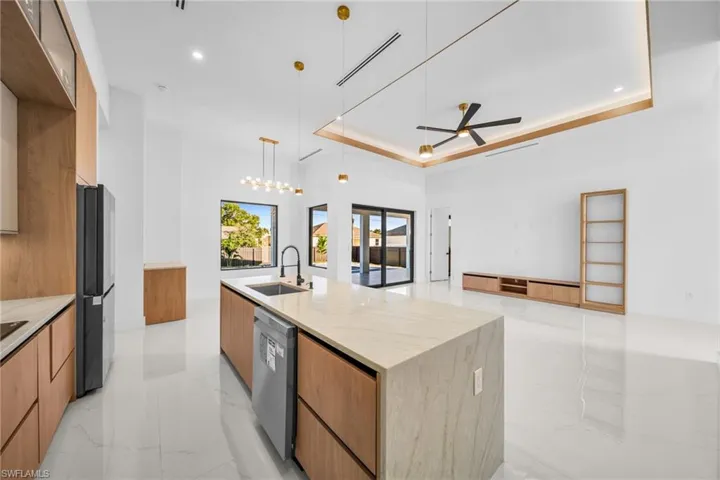 Kitchen with light marble finish floors, a large island, ceiling fan, light stone countertops, and modern cabinets