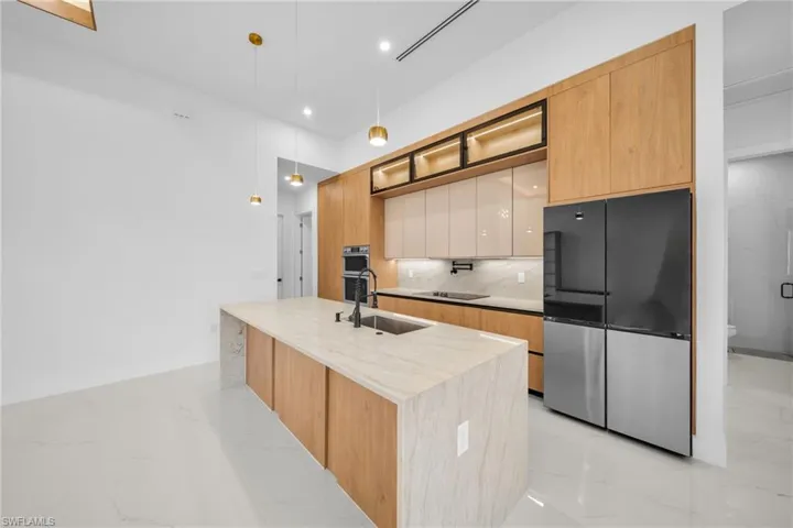 Kitchen featuring decorative light fixtures, light marble finish flooring, light brown cabinets, and recessed lighting