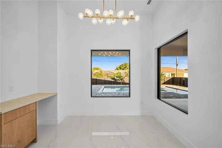 Unfurnished dining area featuring plenty of natural light, light marble finish floors, and a chandelier