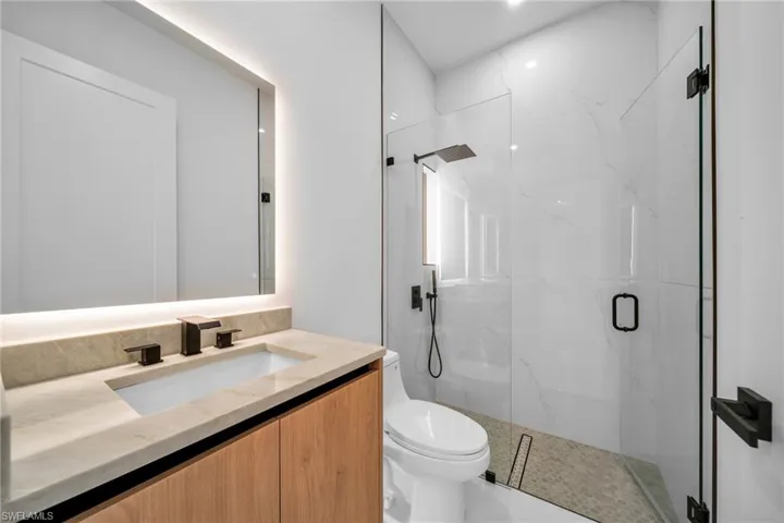 Bathroom featuring vanity and a marble finish shower