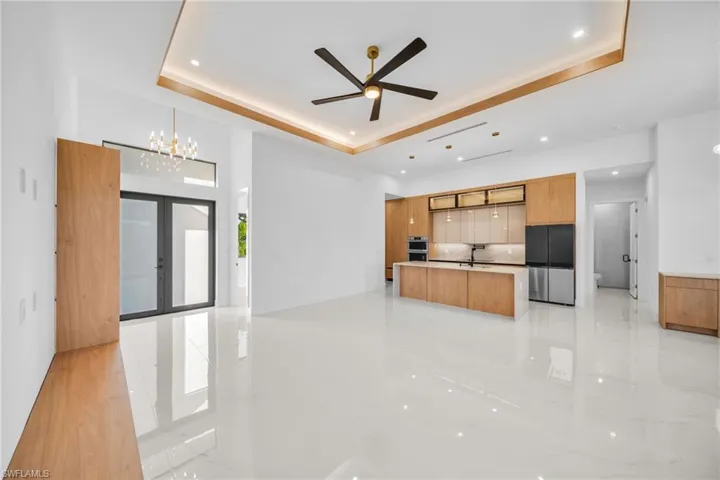 Kitchen with open floor plan, french doors, a kitchen island with sink, modern cabinets, and stainless steel fridge
