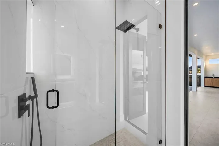 Bathroom with a marble finish shower and recessed lighting