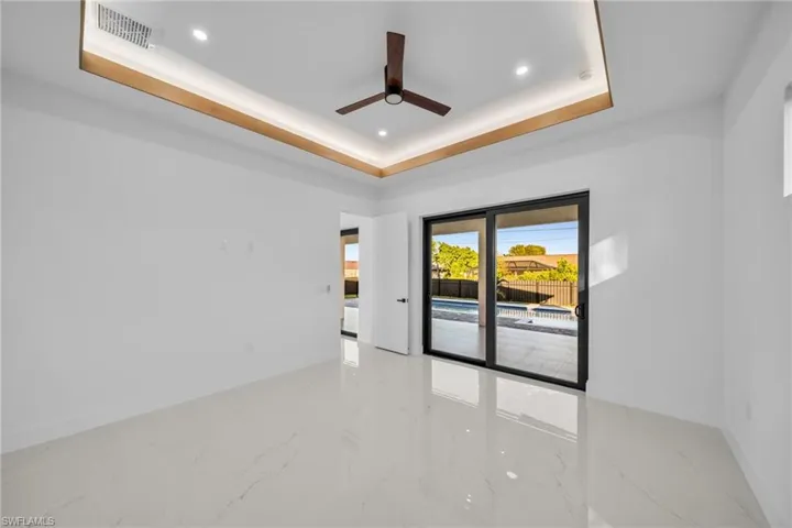 Spare room with light marble finish floors, a tray ceiling, recessed lighting, and ceiling fan