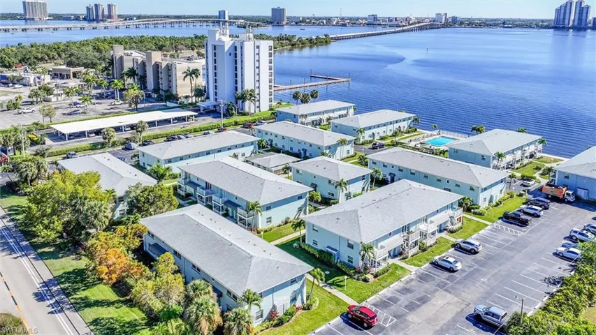 Waterfront community featuring multiple residential buildings, a central swimming pool, and dedicated parking areas