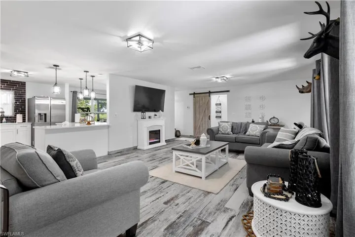 Living room featuring brick wall, light hardwood / wood-style flooring, and a barn door