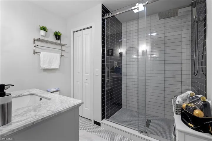 Bathroom featuring tile patterned floors, vanity, and a tile shower