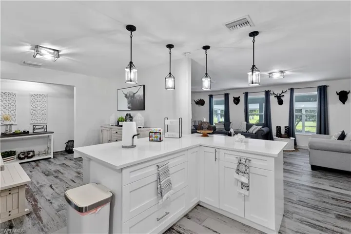 Kitchen featuring white cabinetry, light hardwood / wood-style flooring, and decorative light fixtures