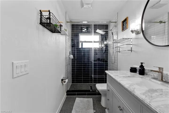 Bathroom featuring tile patterned floors, vanity, a tile shower, and toilet
