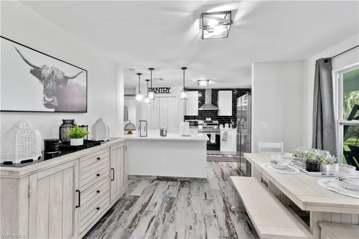 Kitchen featuring tasteful backsplash, stainless steel appliances, wall chimney range hood, kitchen peninsula, and light hardwood / wood-style floors