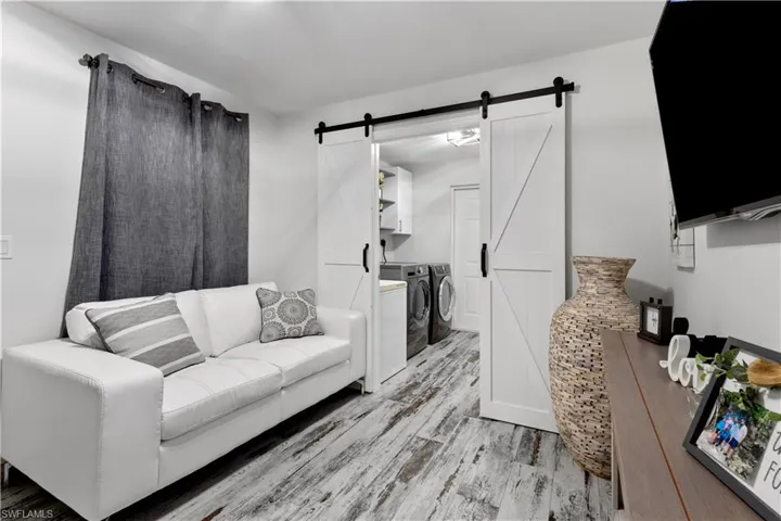 Living room with washing machine and dryer, light wood-type flooring, and a barn door