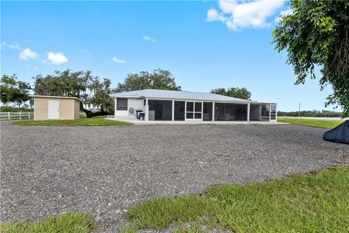 Rear view of property featuring a storage unit and a sunroom
