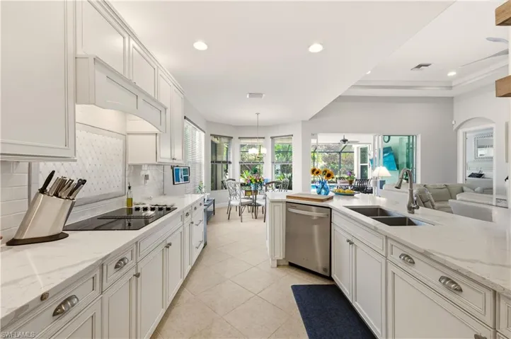 Kitchen with recessed lighting, white cabinets, light stone countertops, open floor plan, and dishwasher