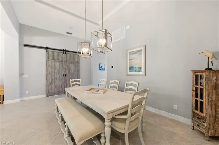 Dining area with a barn door, light tile patterned flooring, and a chandelier