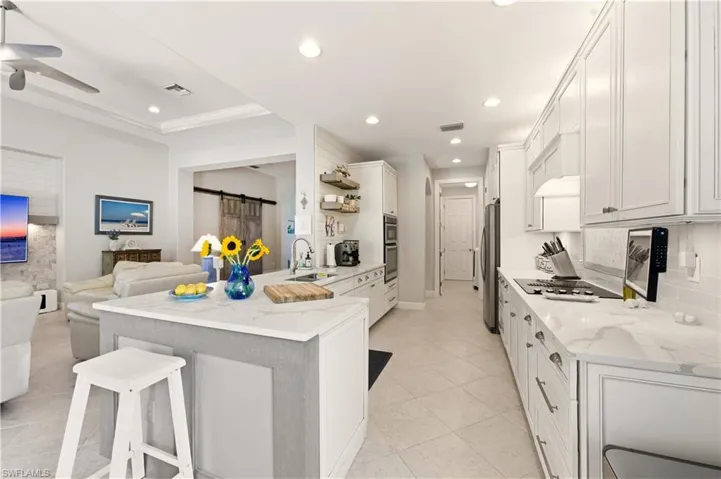 Kitchen featuring a peninsula, a barn door, a kitchen bar, light stone countertops, and recessed lighting