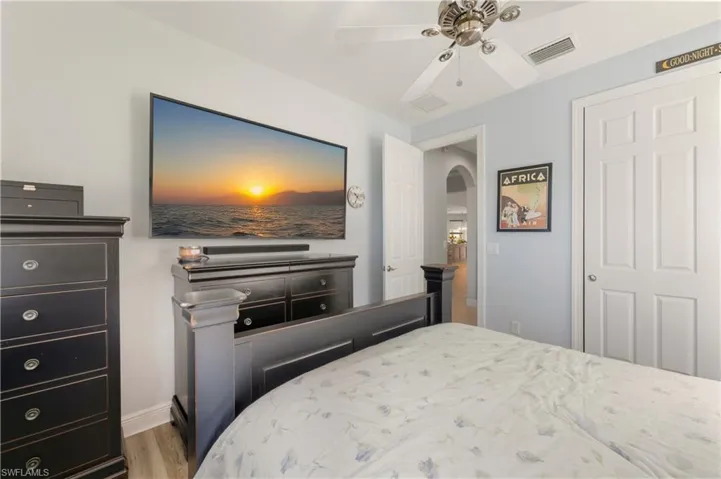 Bedroom with wood finished floors, arched walkways, and ceiling fan