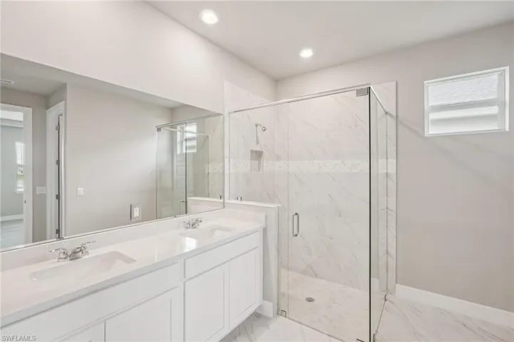 Bathroom with a marble finish shower, double vanity, marble finish floors, recessed lighting, and baseboards
