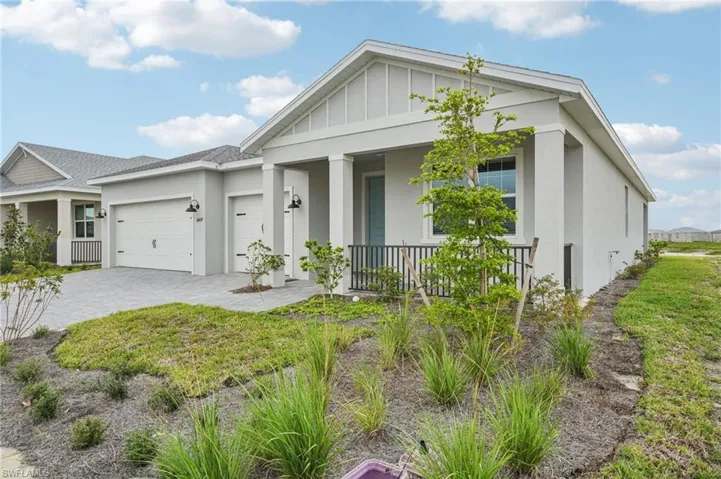 View of front of property with stucco siding, covered porch, a garage, decorative driveway, and board and batten siding