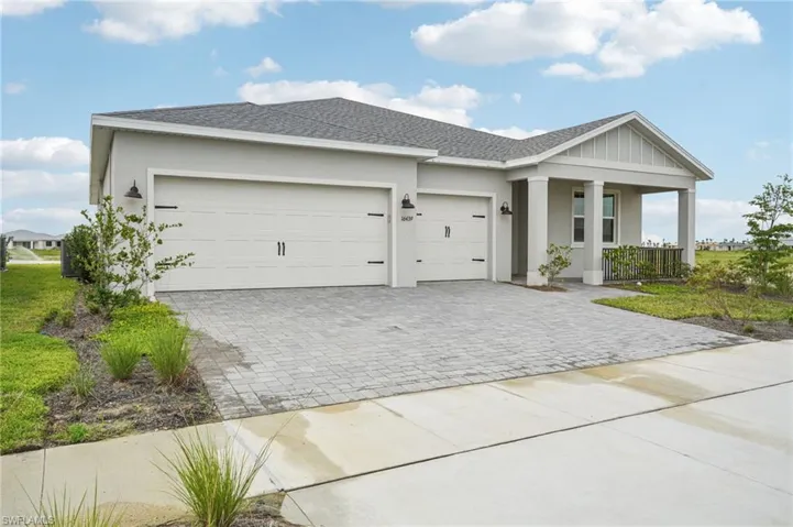 View of front facade with covered porch, decorative driveway, an attached garage, and stucco siding
