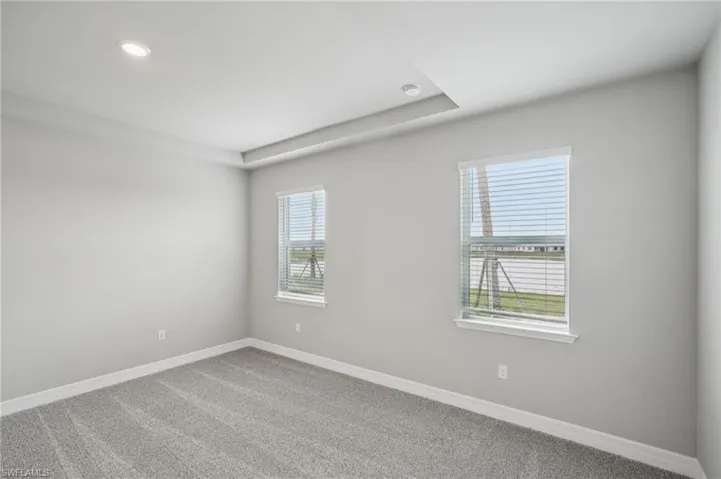Carpeted spare room with baseboards and recessed lighting