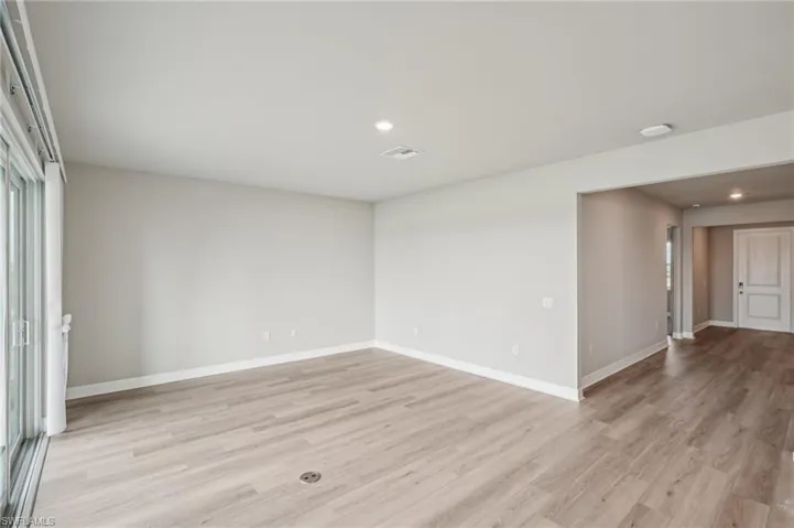Unfurnished room with light wood finished floors, baseboards, and recessed lighting