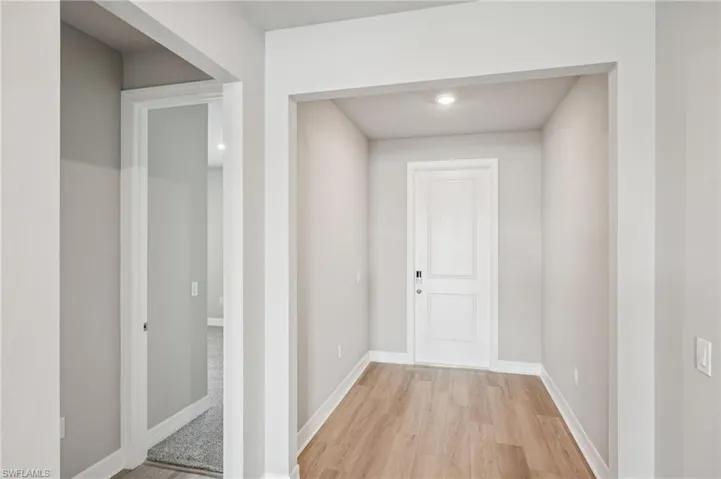 Hallway with light wood-style floors and baseboards
