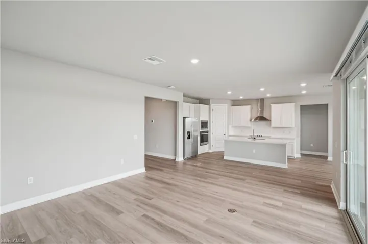 Unfurnished living room featuring recessed lighting, a sink, baseboards, and light wood-type flooring