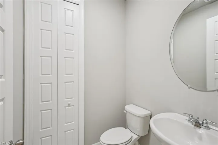 Bathroom featuring a sink, toilet, a closet, and baseboards