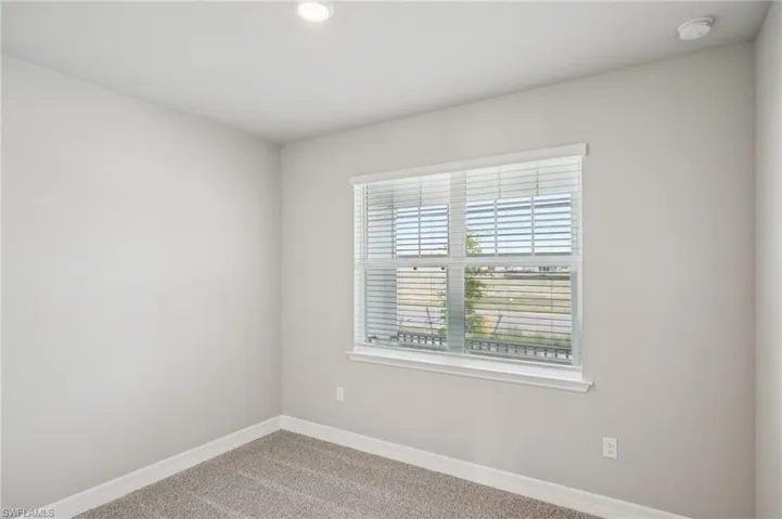 Carpeted spare room featuring baseboards, a smoke detector, and recessed lighting