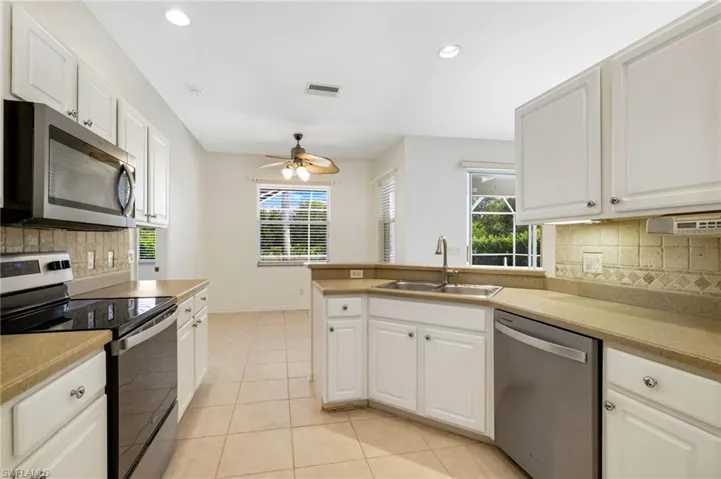 Kitchen with backsplash, appliances with stainless steel finishes, recessed lighting, light tile patterned floors, and a ceiling fan