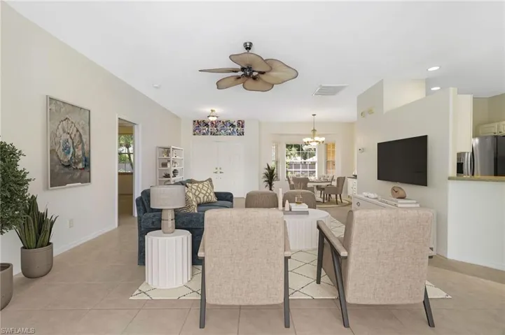 Living area featuring a ceiling fan, light tile patterned floors, and a chandelier