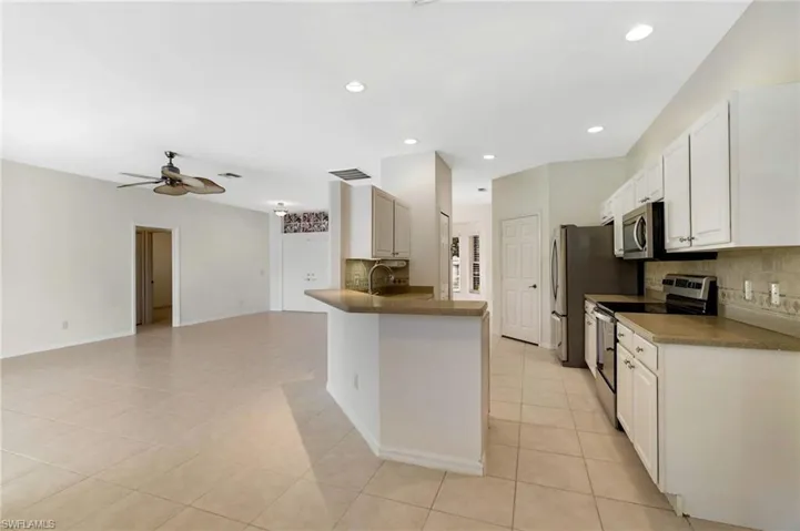 Kitchen with stainless steel appliances, recessed lighting, backsplash, light tile patterned floors, and open floor plan