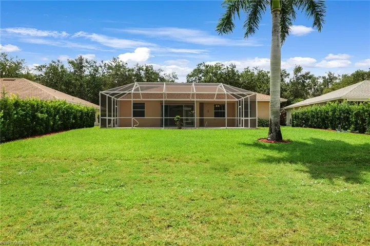 Back of property with a yard and a lanai