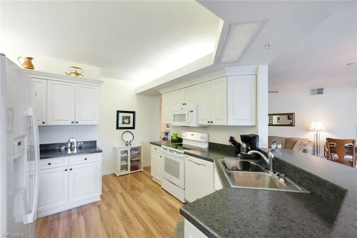 Kitchen featuring sink, white cabinets, light hardwood / wood-style floors, and white appliances