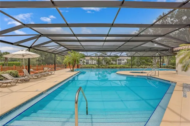 Screened in Lap Pool with a large lanai with tables with umbrellas.