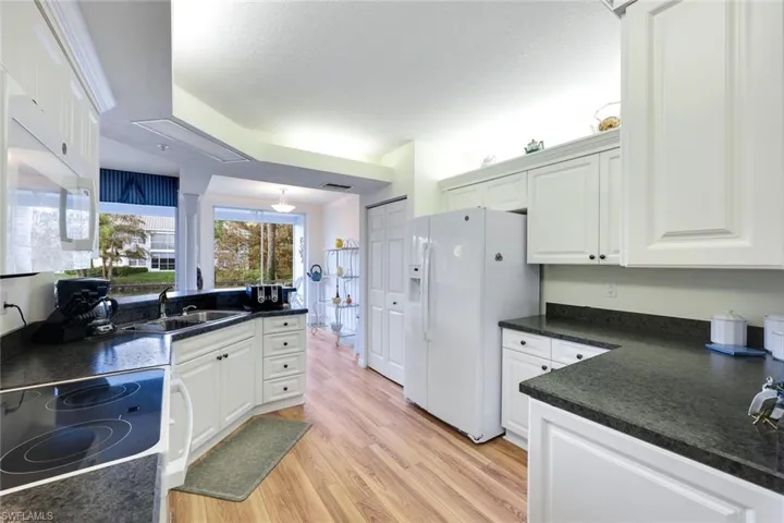 Kitchen featuring white appliances, light hardwood / wood-style floors, white cabinetry, and sink
