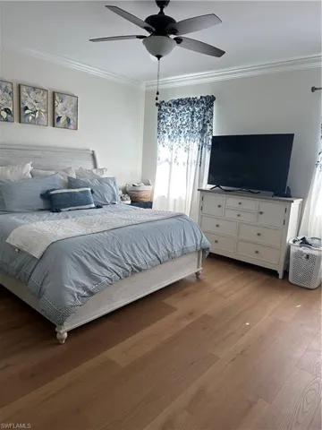Bedroom featuring light wood finished floors, a ceiling fan, and ornamental molding