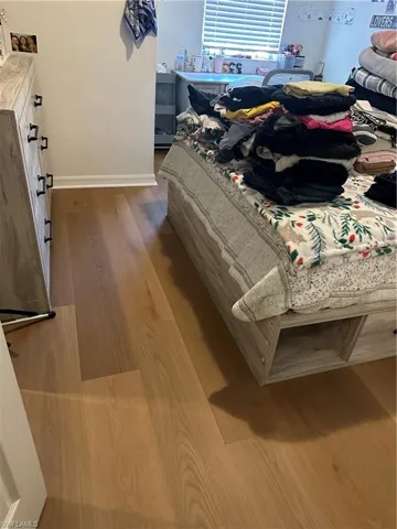 Bedroom with dark wood-style floors and baseboards