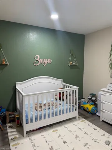 Bedroom featuring a crib and wood finished floors