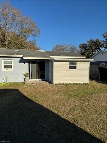 Rear view of property featuring concrete block siding, a patio area, and roof with shingles