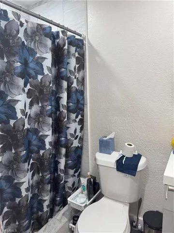 Full bathroom featuring a textured wall, vanity, and a shower with shower curtain