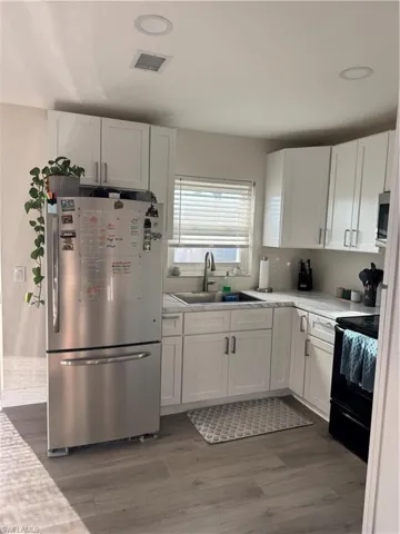 Kitchen with refrigerator, range, white cabinets, dark wood-style flooring, and recessed lighting