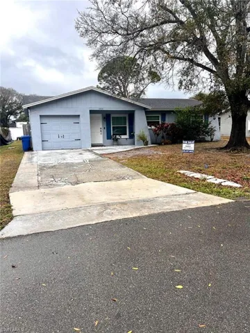 Ranch-style house featuring driveway, an attached garage, and a front lawn
