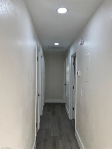 Hallway featuring a textured wall, wood finished floors, and recessed lighting