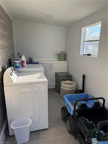 Laundry area with washer and clothes dryer and light tile patterned flooring