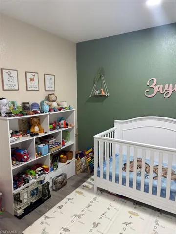 Bedroom featuring light wood-style floors and a crib