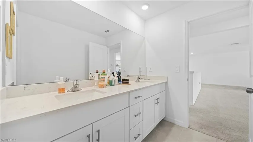 Full bath featuring light colored carpet, double vanity, light tile patterned floors, and recessed lighting